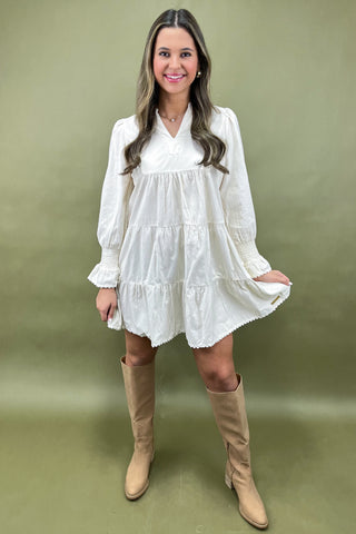 Woman wearing a white dress and beige knee-high boots against a green background
