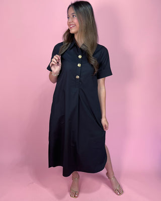 Woman wearing a black dress with gold buttons against a pink background