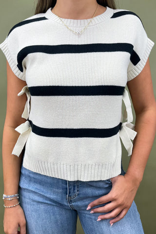Black and white striped knit top with side bow details styled with light wash wide leg frayed hem jeans and gold loafers.