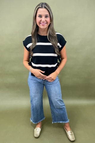 Black and white striped knit top with side bow details styled with light wash wide leg frayed hem jeans and gold loafers