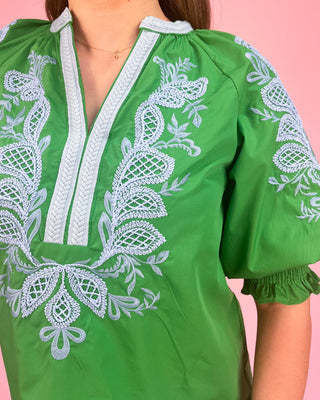 Green blouse with white embroidery on a pink background