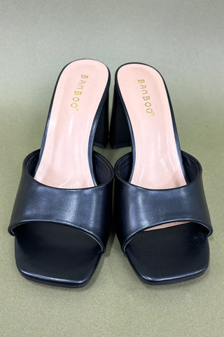 Pair of black open-toe shoes with 'Bamboo' branding on a green background