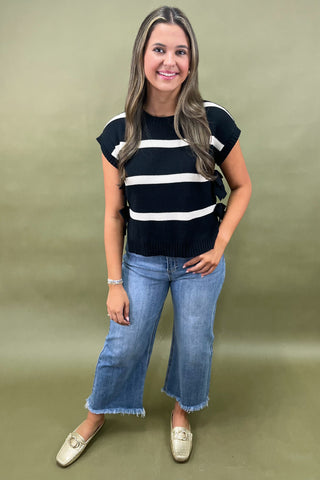 Black and white striped knit top with side bow details styled with light wash wide leg frayed hem jeans and gold loafers