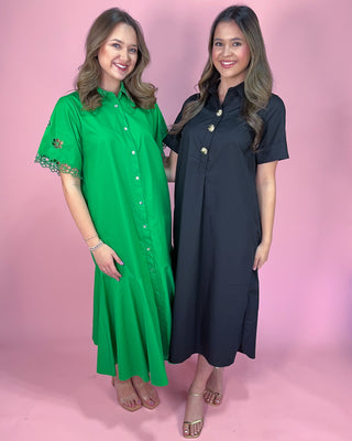Two women wearing green and black dresses against a pink background