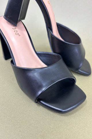 Black high-heeled shoes on a light green background