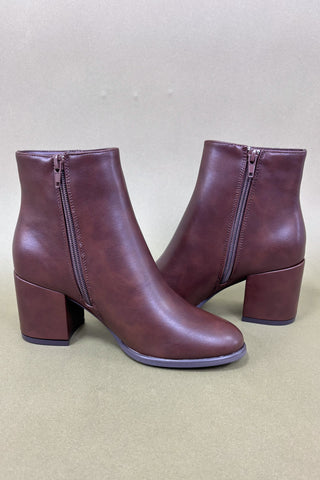 Pair of brown ankle boots with block heels on a beige background