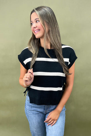 Black and white striped knit top with side bow details styled with light wash wide leg frayed hem jeans and gold loafers