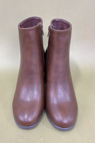 Pair of brown leather ankle boots on a beige background