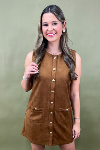Woman wearing a brown dress with buttons on a green background