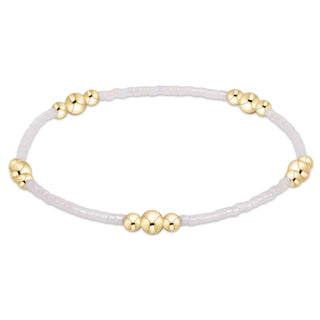 White bracelet with gold beads on a white background
