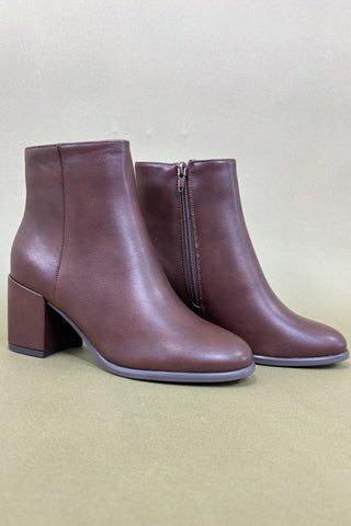 Pair of brown ankle boots on a beige background