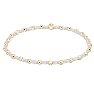 Beaded bracelet with gold and white beads on a white background