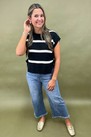 Black and white striped knit top with side bow details styled with light wash wide leg frayed hem jeans and gold loafers
