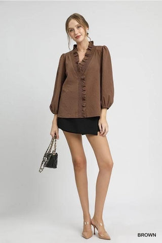 Woman wearing a brown blouse and black skirt with beige heels on a white background