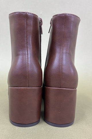 Pair of brown leather ankle boots on a beige background