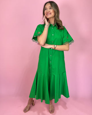 Woman wearing a green dress with lace trim on a pink background