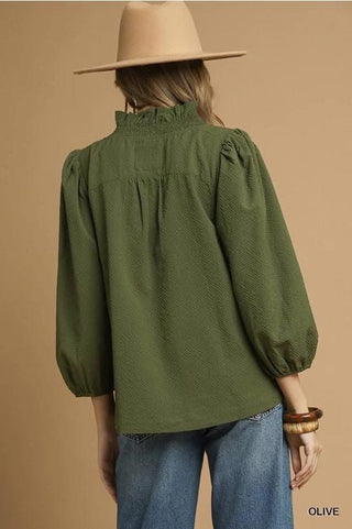 Person wearing a green blouse and beige hat on a beige background