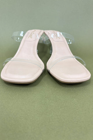 Pair of light pink flat shoes on a green background