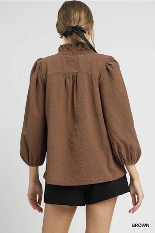 Brown blouse with puff sleeves worn by a person on a white background