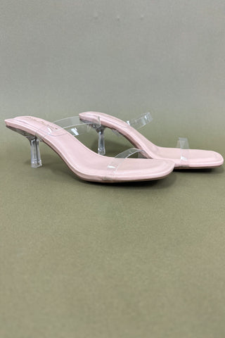 Pink high-heeled sandals with clear straps on a gray background