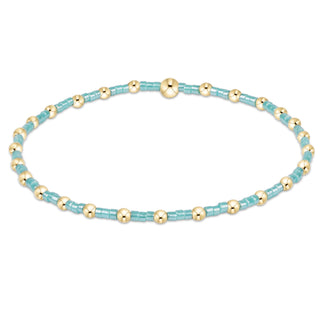 Bracelet with alternating turquoise and gold beads on a white background
