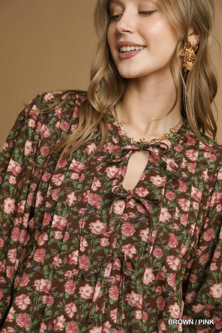 Woman wearing a floral dress with pink and green flowers on a beige background