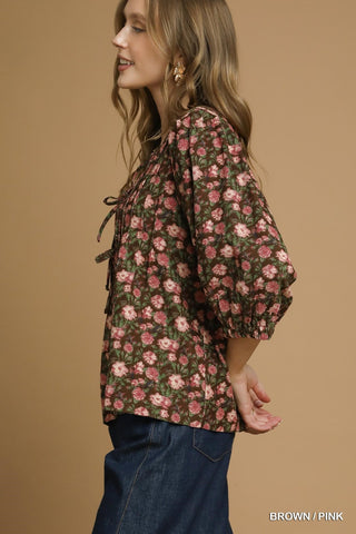 Woman wearing a floral blouse with brown and pink flowers on a beige background
