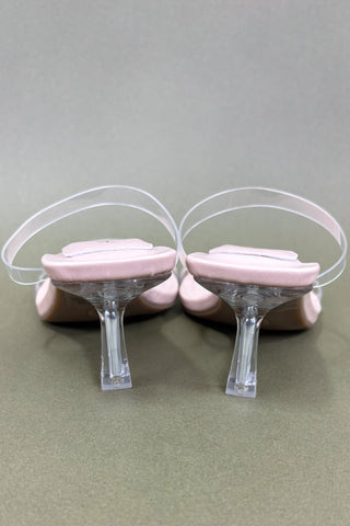 Pink high heels with clear plastic stands on a gray background