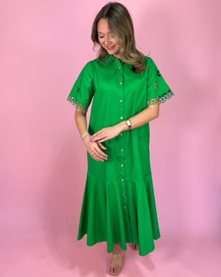 Woman wearing a green dress with lace trim on a pink background