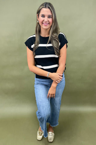 Black and white striped knit top with side bow details styled with light wash wide leg frayed hem jeans and gold loafers