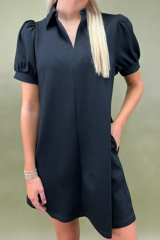 Woman wearing a black dress with puff sleeves against a green background