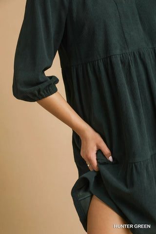 Hunter green dress with long sleeves on a beige background