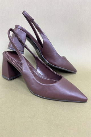 Pair of maroon high-heeled shoes on a beige background