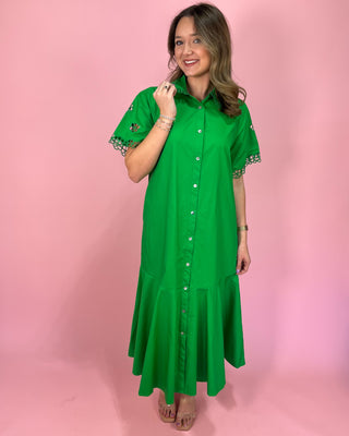 Woman wearing a green dress with lace sleeves against a pink background