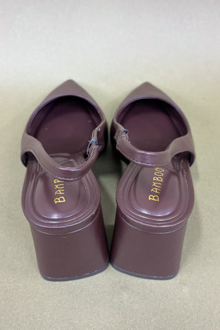Pair of maroon sandals with branding on a beige background