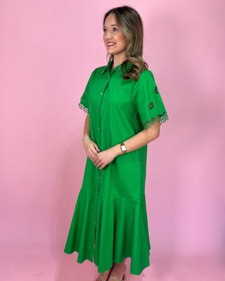 Woman wearing a green dress with lace details on a pink background