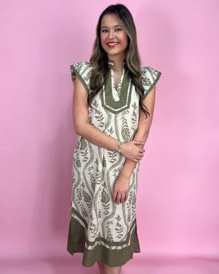 Woman wearing a green and white patterned dress against a pink background