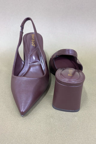 Pair of brown high-heeled shoes with a matching cylindrical box on a beige background