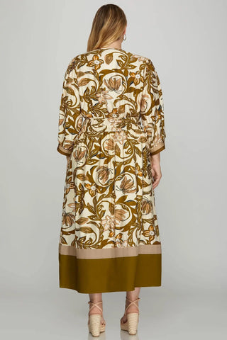 Woman wearing a long, patterned dress with a neutral background