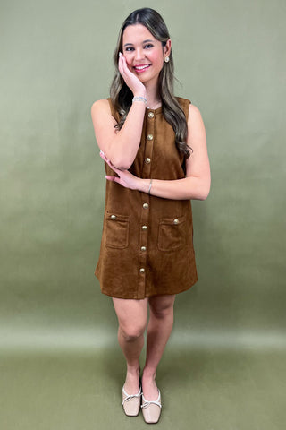 Woman wearing a brown suede dress against a green background