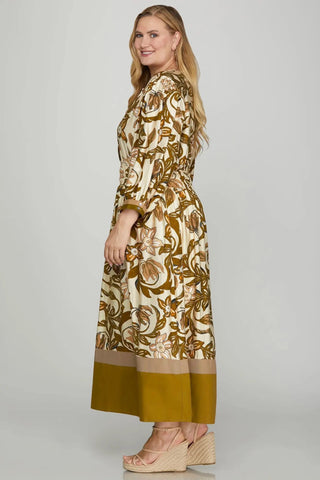 Woman wearing a long, patterned dress with a plain background