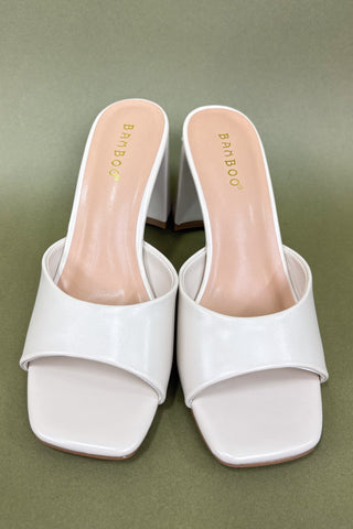 White high-heeled shoes with 'Bamboo' branding on a green background