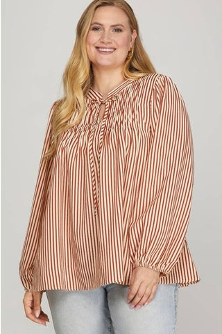 Woman wearing a striped blouse with long sleeves on a plain background