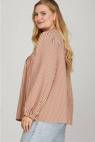 Woman wearing a striped shirt and jeans on a plain background