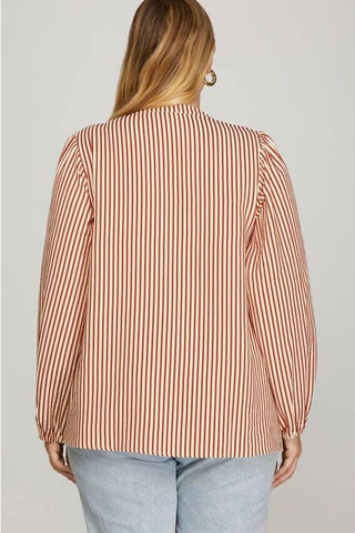 Woman wearing a striped blouse with long sleeves on a plain background