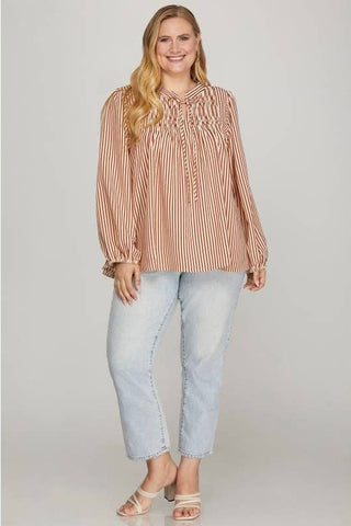 Woman wearing a striped blouse and light blue jeans on a plain background