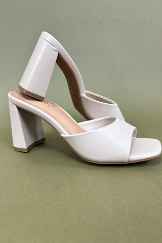 White high-heeled shoes on a green background