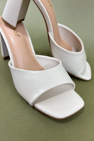 White open-toe high-heeled shoes on a green background