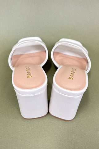 White sandals with 'Bamboo' branding on a green background