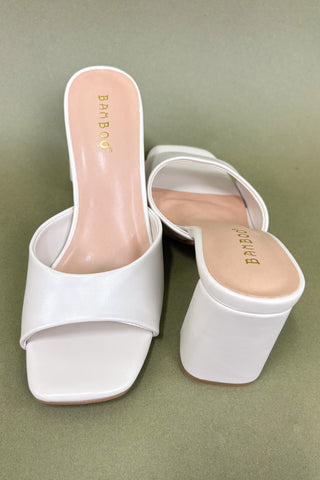 White high-heeled shoes on a green background